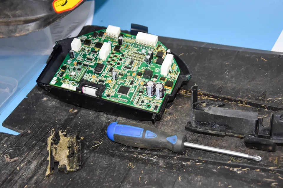 Smutsigt plastskydd med ett trasigt kretskort till gräsklippare.